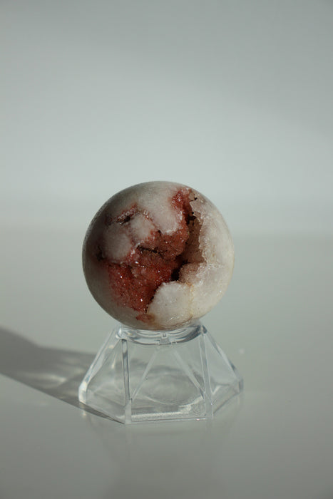A deep pink and pale white amethyst mini sphere with shimmering pink druzy