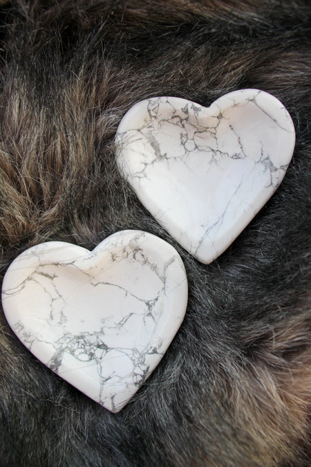 Two Heart shaped Howlite bowls sit on a grey fur background in the afternoon light