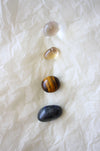 This image shows the four tumble stones of the Gemini Zodiac Crystal Kit, which are (from top to bottom): Clear Quartz, yellow Citrine, brown and yellow Tigers Eye and green Aventurine.  