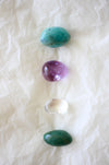 This image shows the four tumble stones of the Virgo Zodiac Crystal Kit, which are (from top to bottom): Amazonite, Amethyst, Clear Quartz and Aventurine