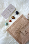  This image shows the 23 Urban Sagittarius Zodiac Kit in flat lay. On the bottom right is the 23 Urban jute bag which all products come in. Then are the four Sagittarius tumble stones, which are Blue Sunstone, Tigers Eye, Carnelian and Amazonite. Next to the tumble stones on the bottom right is the Sagittarius Zodiac Crystal Kit card, outlining the traits of Sagittarius and explaining the properties of the crystals. 