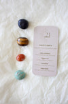  To the left of this image are the four Sagittarius Zodiac Crystal Kit tumble stones, which are Blue Sunstone, Tigers Eye, Carnelian and Amazonite. Next to the tumble stones is a Sagittarius Zodiac Crystal Kit card, outlining the traits of Sagittarius and explaining the properties of the crystals. 