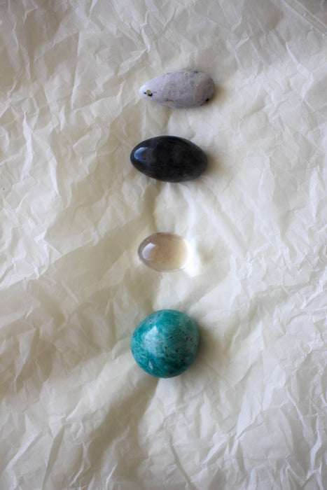 This image shows the four tumble stones of the Aquarius Zodiac Crystal Kit, which are (from top to bottom): Moonstone, Labradorite, Clear Quartz, Amazonite