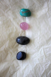This image shows the four tumble stones of the Pisces Zodiac Crystal Kit, which are (from top to bottom): Amazonite, Rose Quartz, Labradorite, Blue Sunstone 