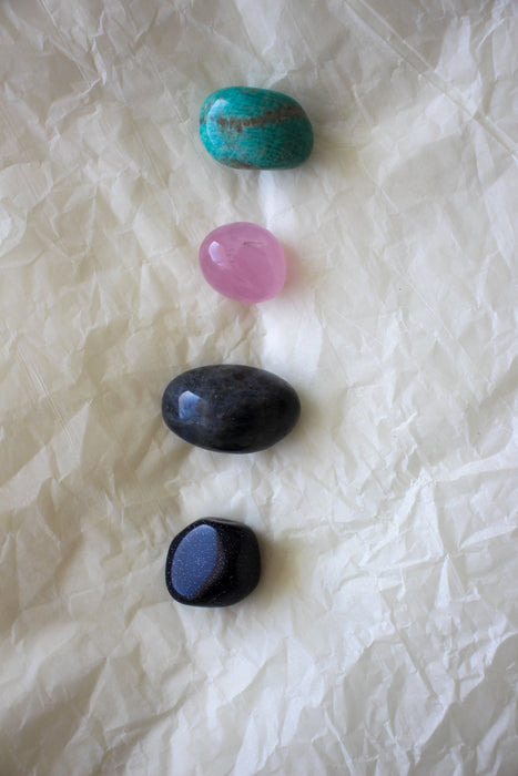 This image shows the four tumble stones of the Pisces Zodiac Crystal Kit, which are (from top to bottom): Amazonite, Rose Quartz, Labradorite, Blue Sunstone 