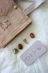 This image shows the 23 Urban Leo Zodiac Kit in flat lay. On the top left is the 23 Urban jute bag which all products come in. Then are the four Leo tumble stones, which are Carnelian, Citrine, Tigers Eye, Pyrite. Next to the tumble stones on the bottom right is the Leo Zodiac Crystal Kit card, outlining the traits of Leo and explaining the properties of the crystals. 