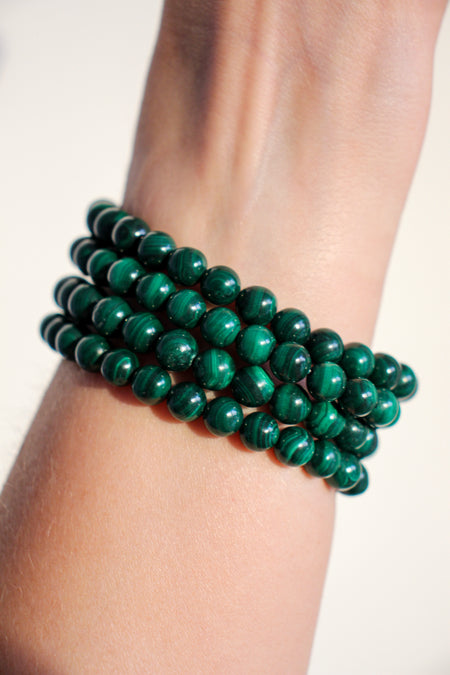Four Malachite bracelets in a stack, showing off their deep green banding 