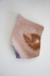 A pink ocean jasper slab sits on a white table
