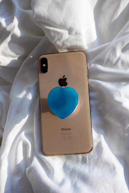 Blue Agate Heart Crystal Phone Grip on the back of a rose gold iPhone on a white background