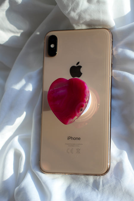 Pink Agate Heart Crystal Phone Grip on the back of a rose gold iPhone on a white background