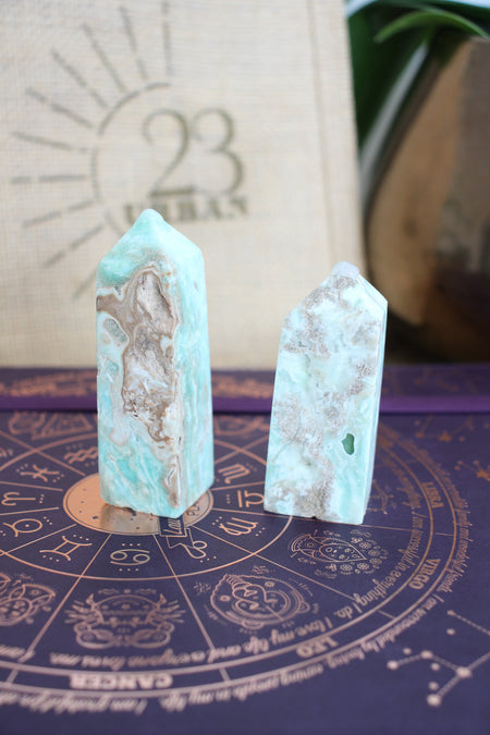 Two pale blue and soft brown Caribbean Calcite towers sit on a purple book, in front of a 23 Urban branded jute bag