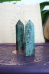 Two Ruby in Kyanite towers stand on a purple surface in front of a 23 Urban branded jute bag