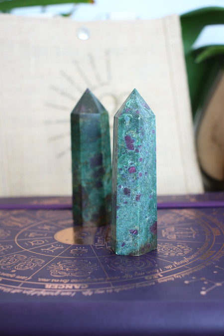 Two Ruby in Kyanite towers stand on a purple surface in front of a 23 Urban branded jute bag