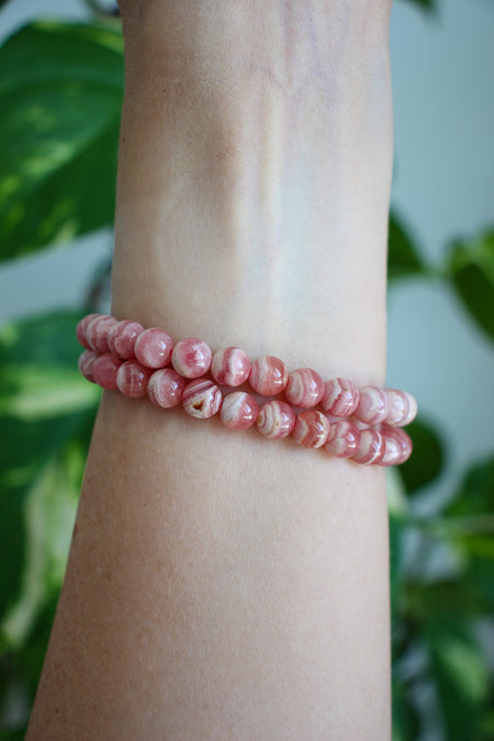 Two beautiful pink and cream banded Rhodochrosite bracelets stacked on a wrist 