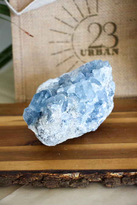A pale blue Celestite cluster on a brown wooden table