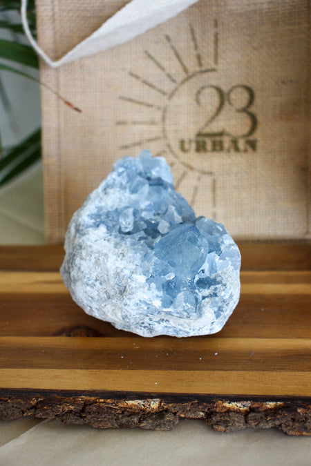 A pale blue Celestite cluster on a brown wooden table