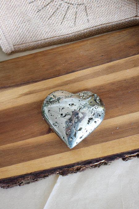 A golden pyrite heart is plated on a brown wooden table