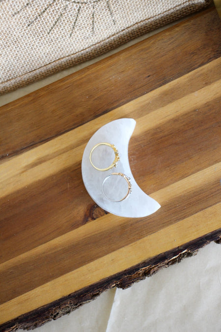 Moon shaped selenite charging plate on a brown wooden table