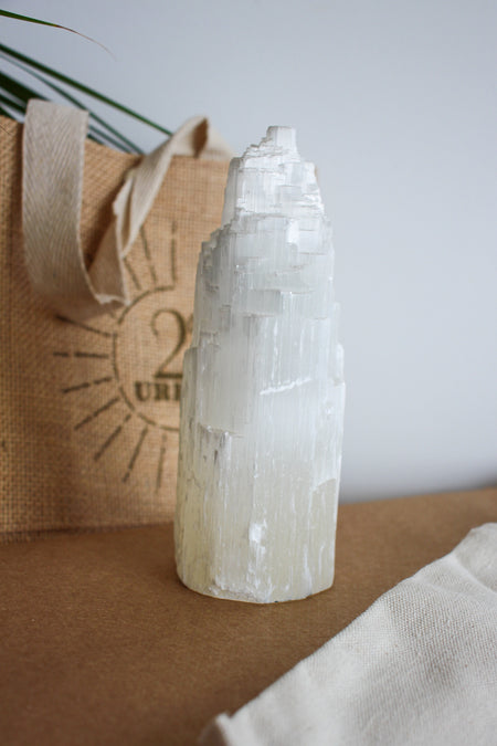 A white Selenite tower in medium size of 15cm high. The Selenite is cut so the long jagged planes are visible, allowing it to reflect light and appear to glow. Dubai crystals. 23 Urban. 