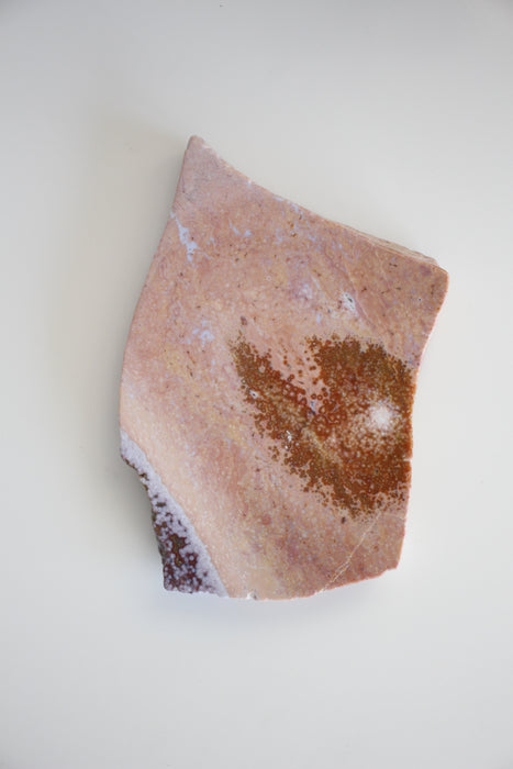 A pink ocean jasper slab sits on a white table