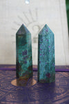 Two Ruby in Kyanite towers stand on a purple surface in front of a 23 Urban branded jute bag