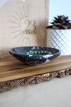 A beautiful glossy black marble bowl containing the fossils of Ammonites and Orthoceras