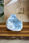 A pale blue Celestite cluster on a brown wooden table